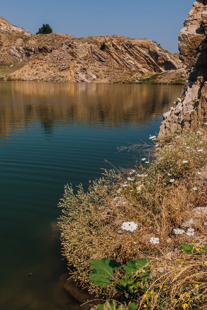 A calm lake surrounded by rocky terrain and sparse vegetation.