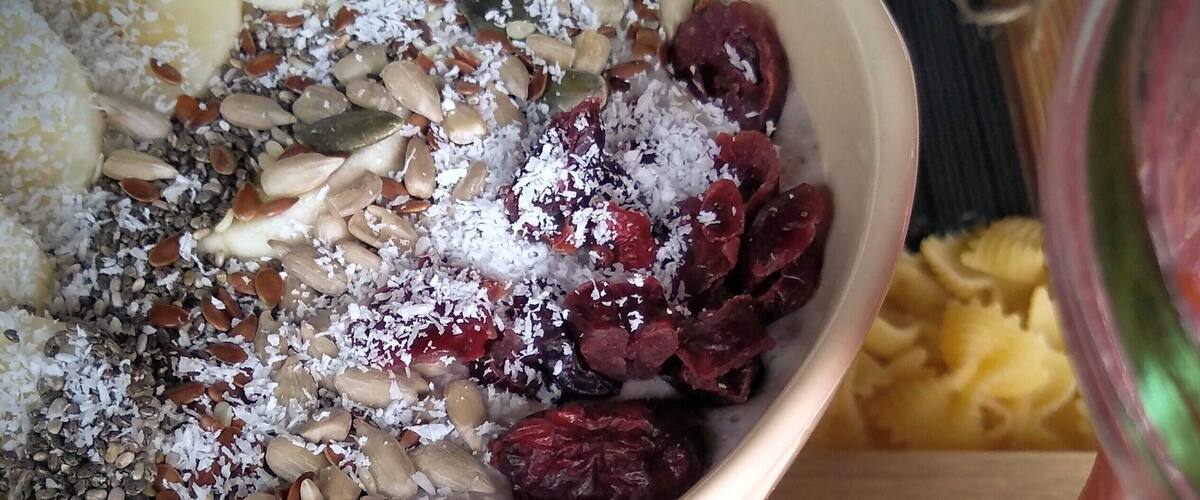 A bowl of cereal with various toppings like nuts, seeds, and dried fruits.