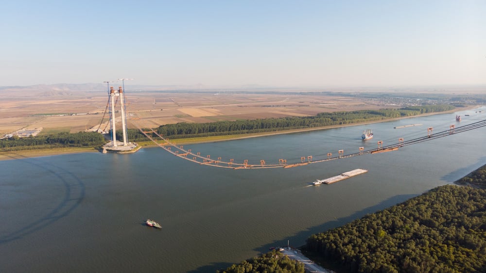 Panoramic aerial drone view from above of the suspended bridge over danube river, under construction, between Braila and Tulcea cities in Romania
