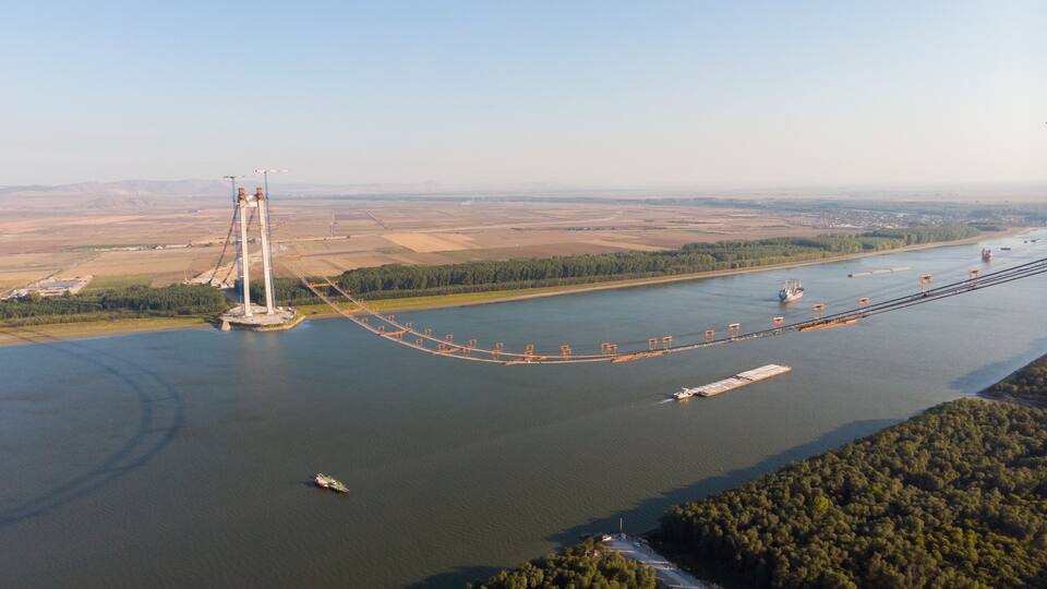 Panoramic aerial drone view from above of the suspended bridge over danube river, under construction, between Braila and Tulcea cities in Romania