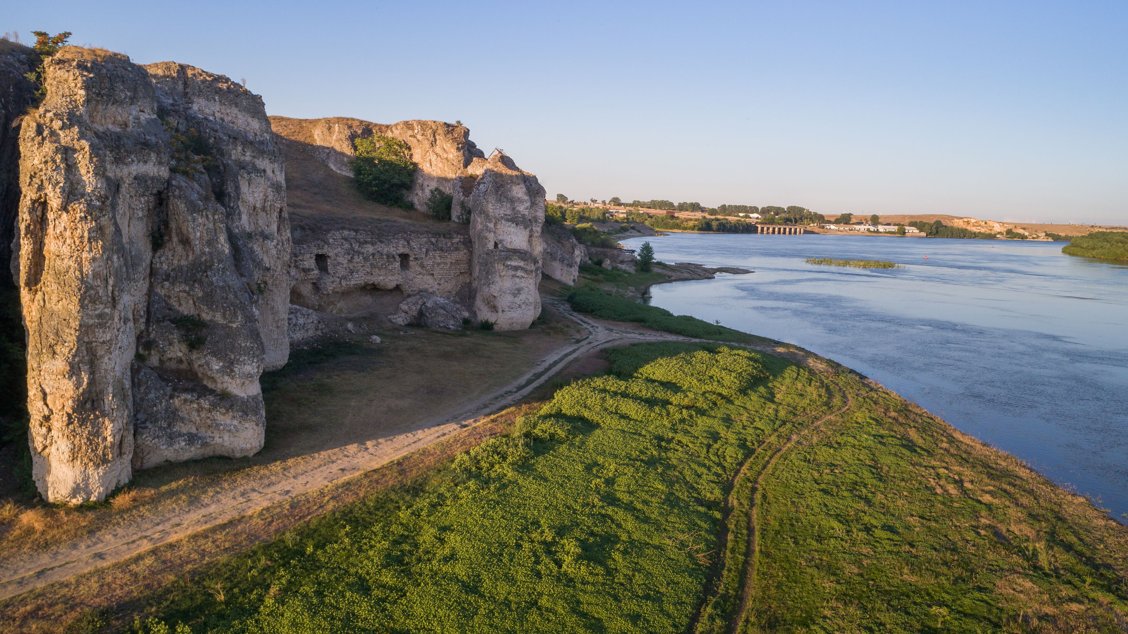 A riverbank with cliffs and a path.