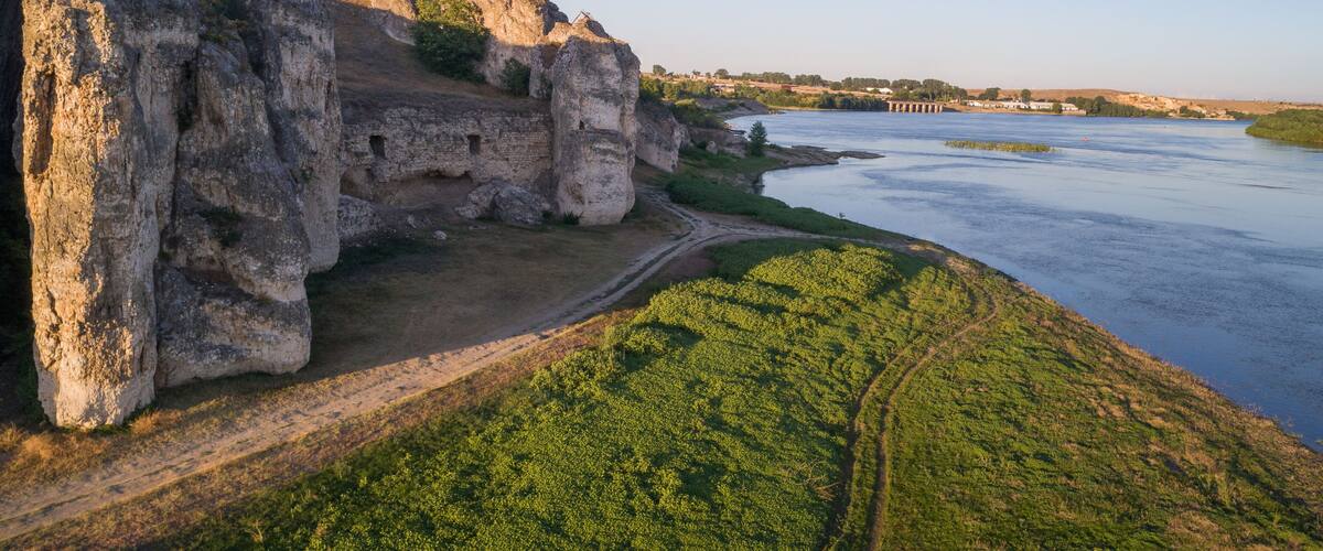 A riverbank with cliffs and a path.