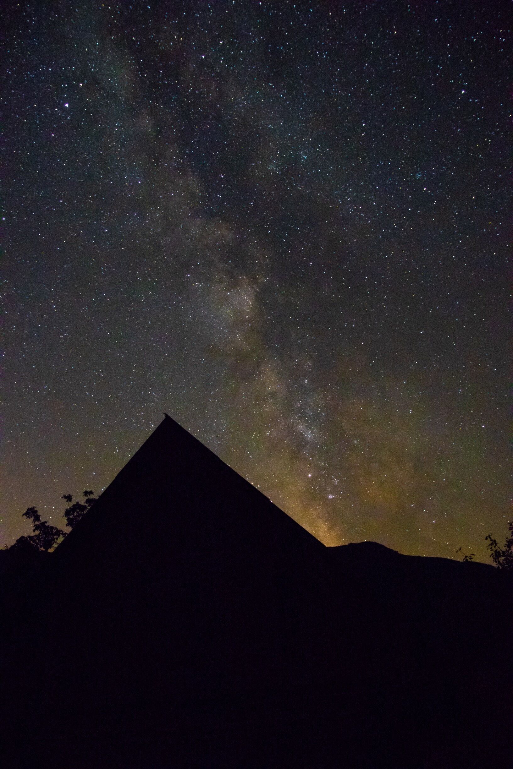 A night sky filled with stars and the Milky Way over a mountain silhouette.
