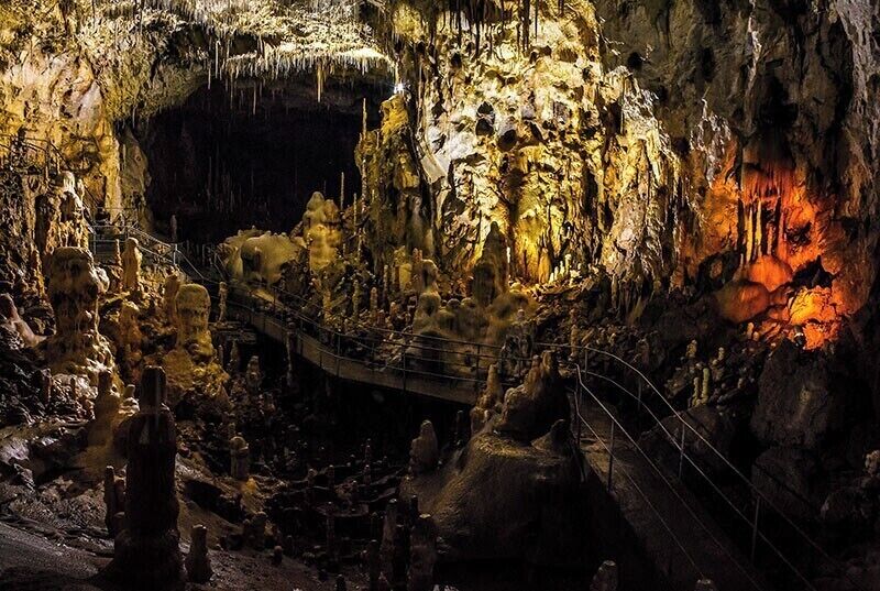 A cave with stalactites and stalagmites, a viewing platform, and a rope bridge.