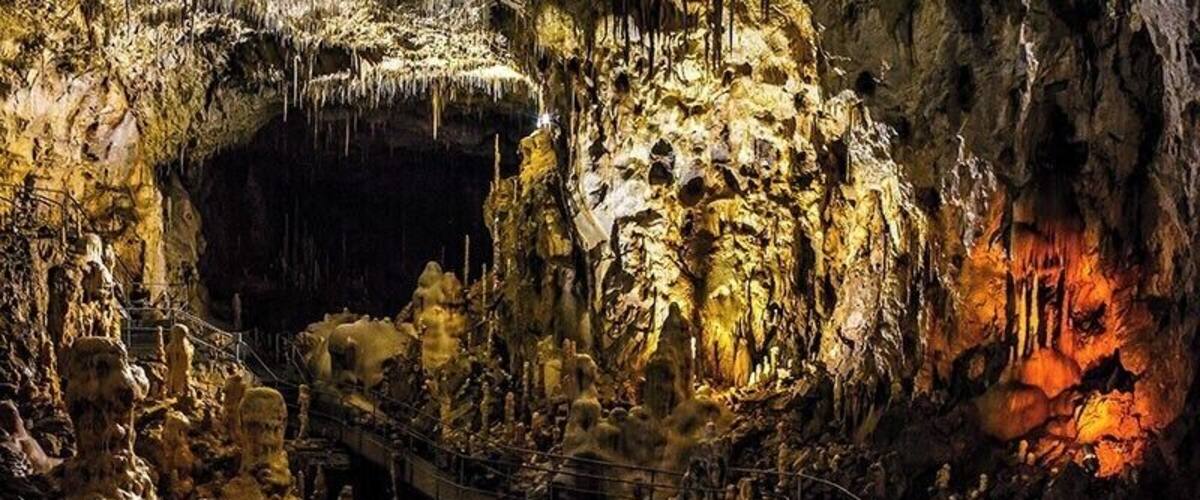 A cave with stalactites and stalagmites, a viewing platform, and a rope bridge.