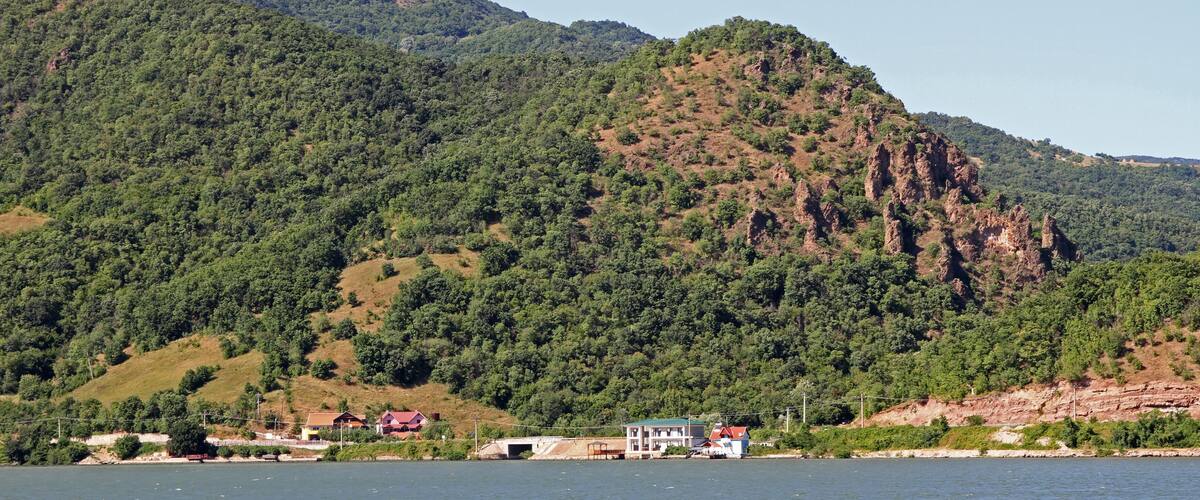 A lake with a mountain in the background and a small settlement with houses and a boat.