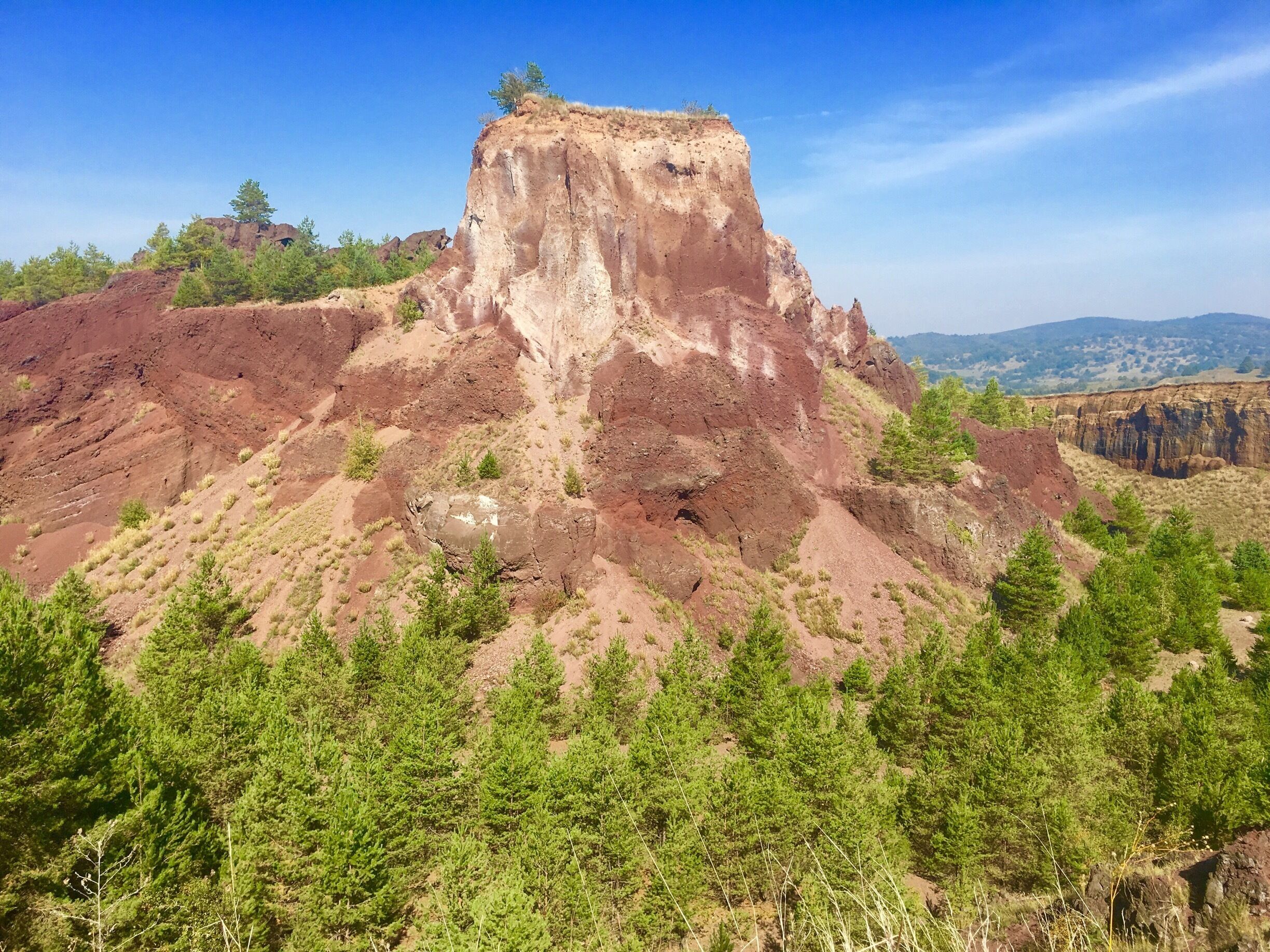 A rugged mountain with a prominent rocky peak, surrounded by dense green forests.