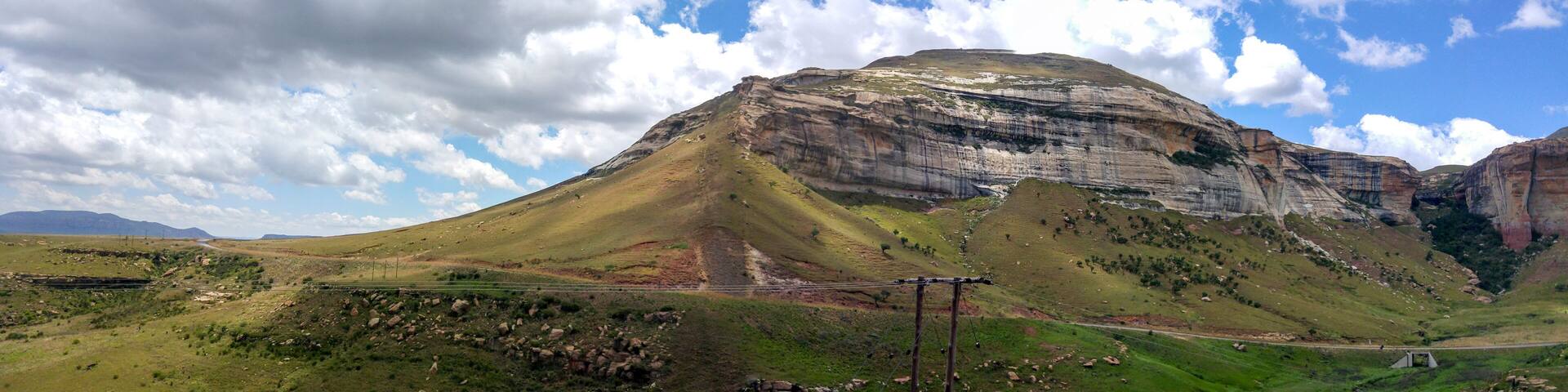 A mountain with a road and power lines in the foreground.