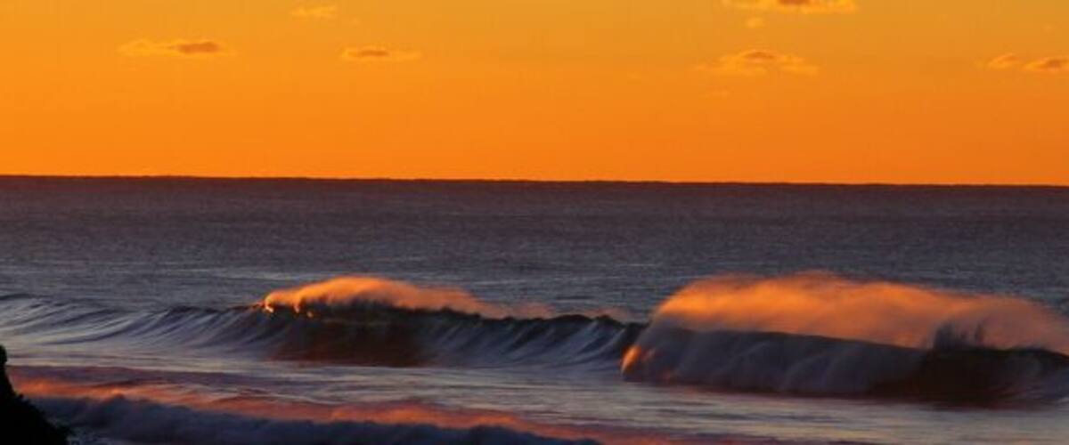 A sunset over the ocean with waves.