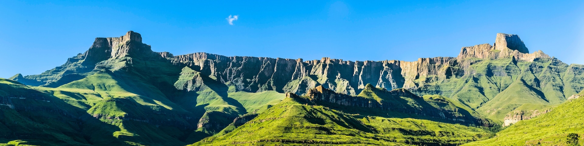 A mountainous landscape with green valleys and rocky cliffs.