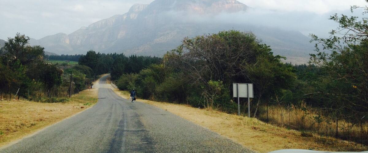A road leading to a mountain with a person walking.