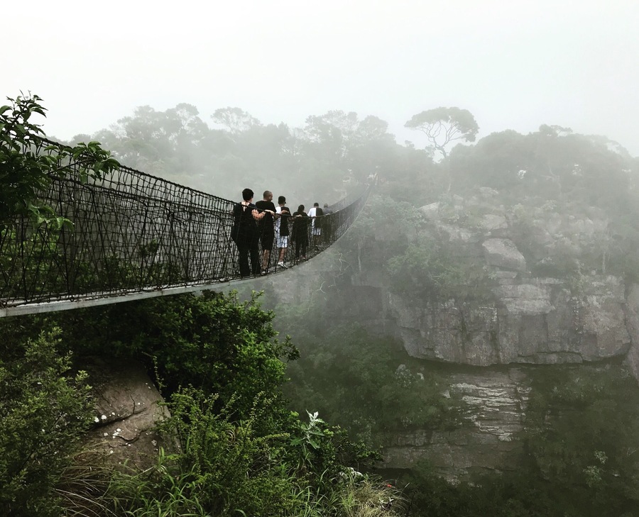 Hanging Bridge disappearing in the rain mist over an extremely high tropical gorge.