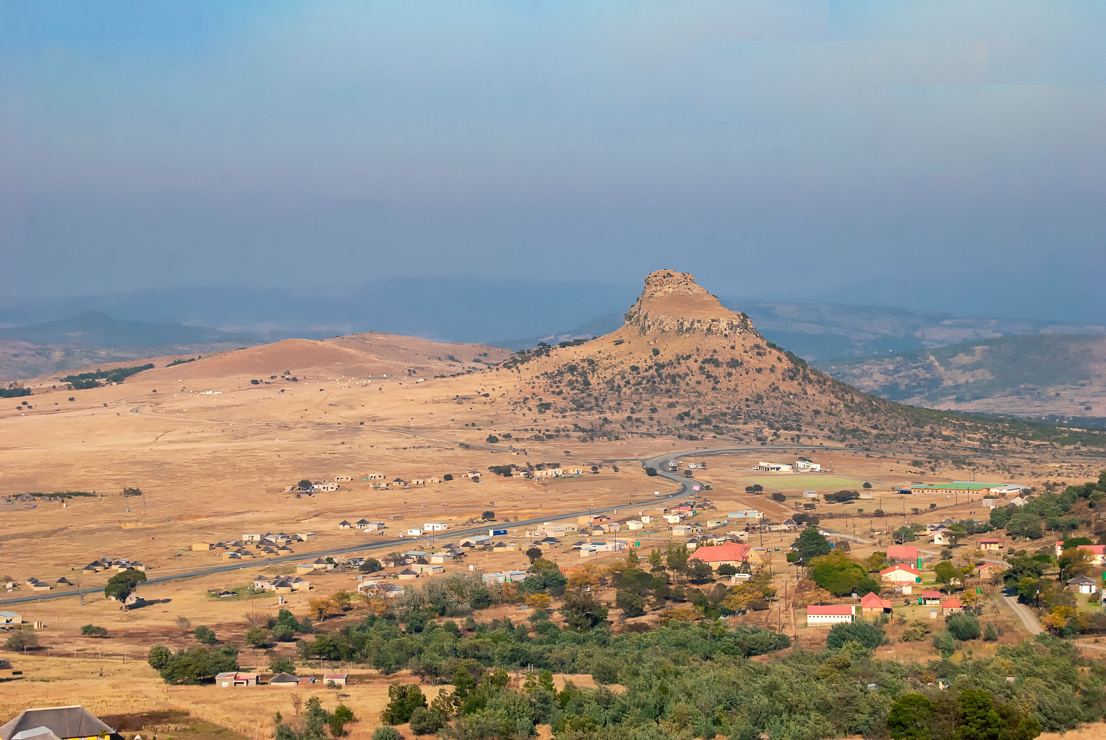 A town nestled in a valley with a prominent hill in the background.
