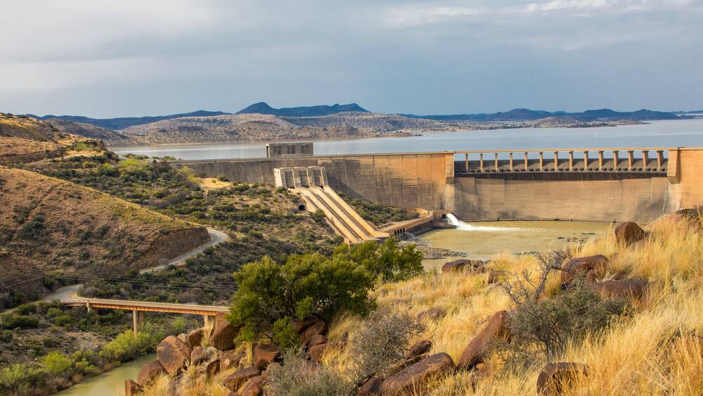 Un barrage doté d’un déversoir, une rivière et un paysage montagneux.