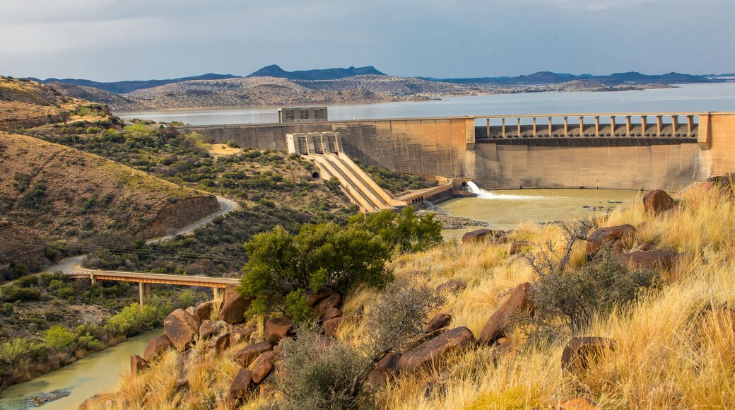 Un barrage doté d’un déversoir, une rivière et un paysage montagneux.