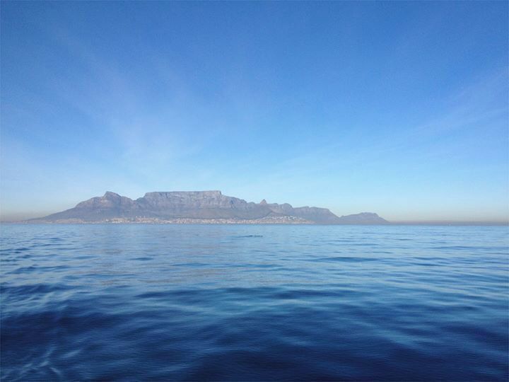 A calm sea with a distant mountain range and a clear sky.