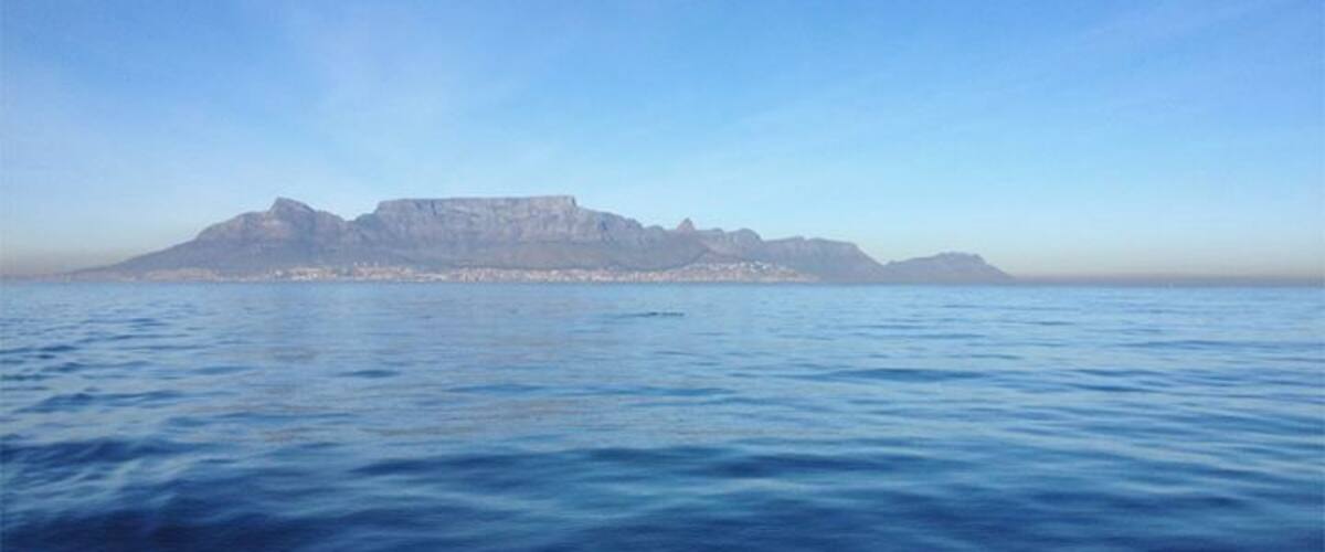 A calm sea with a distant mountain range and a clear sky.