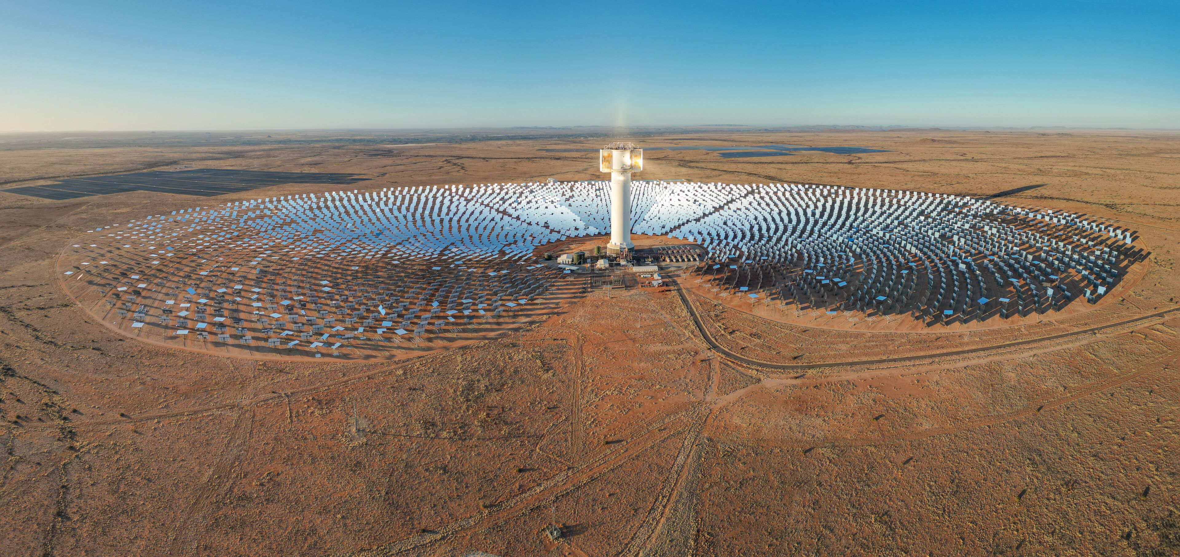 Expansive array of mirrors surround Khi Solar One concentrated solar tower in dry desert landscape of South Africa