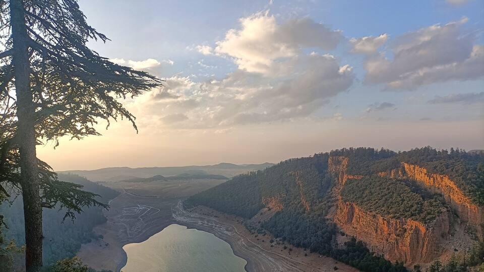 A valley with a river, cliffs, and a forested area.