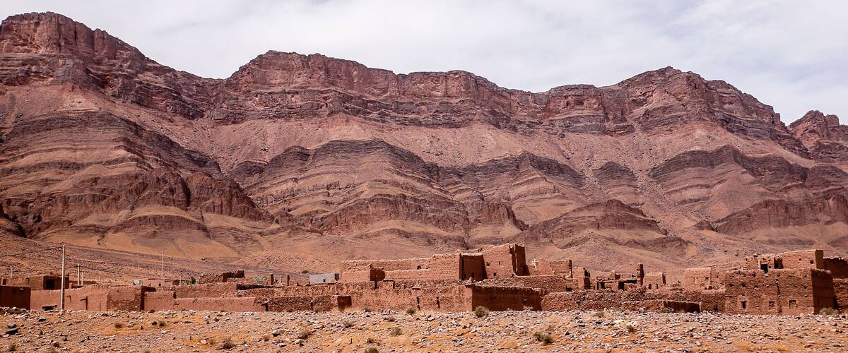 A desert landscape with ancient ruins and layered rock formations.