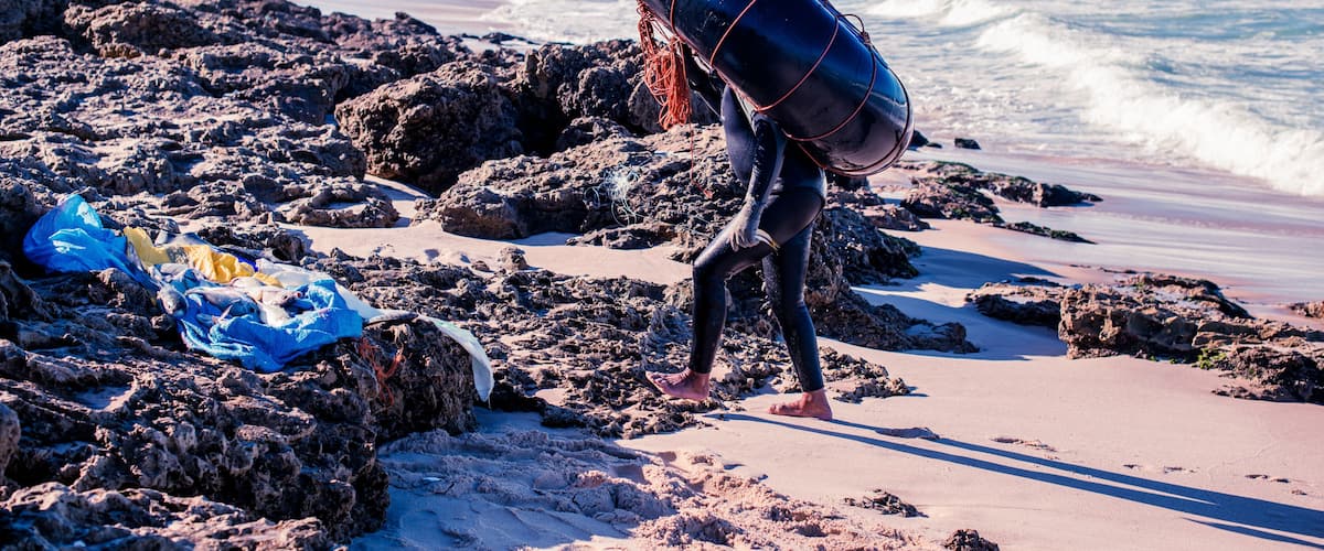Une plage rocheuse avec des vagues, une tour de surveillance des sauveteurs et une personne qui porte une bouée.