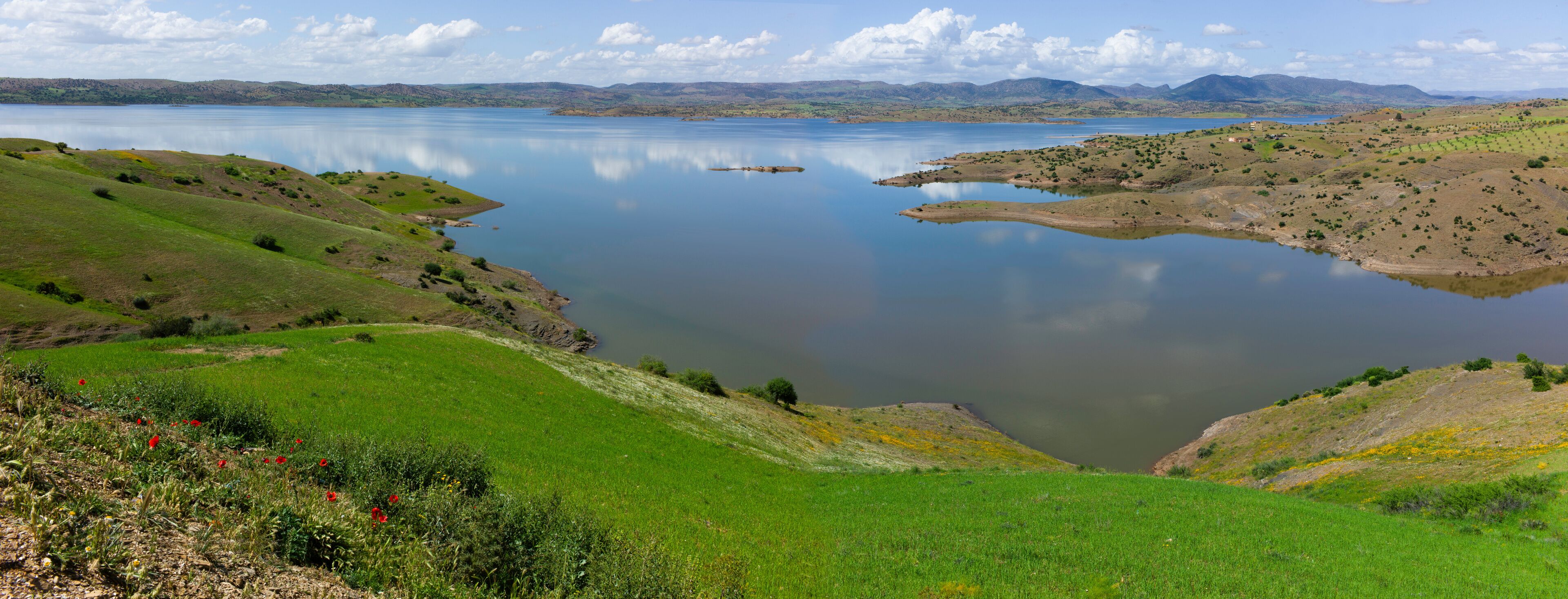 A lake surrounded by green hills and mountains.