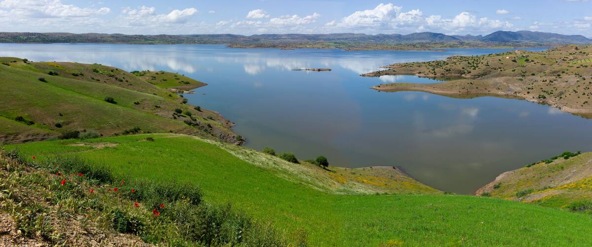A lake surrounded by green hills and mountains.