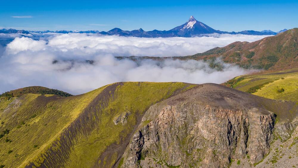 Aerial picture with drone of the natural landscape of the valleys covered with clouds and the volcanoes Tronador and Puntiagudo in the background. Antillanca, Osorno, Chile