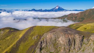 Aerial picture with drone of the natural landscape of the valleys covered with clouds and the volcanoes Tronador and Puntiagudo in the background. Antillanca, Osorno, Chile