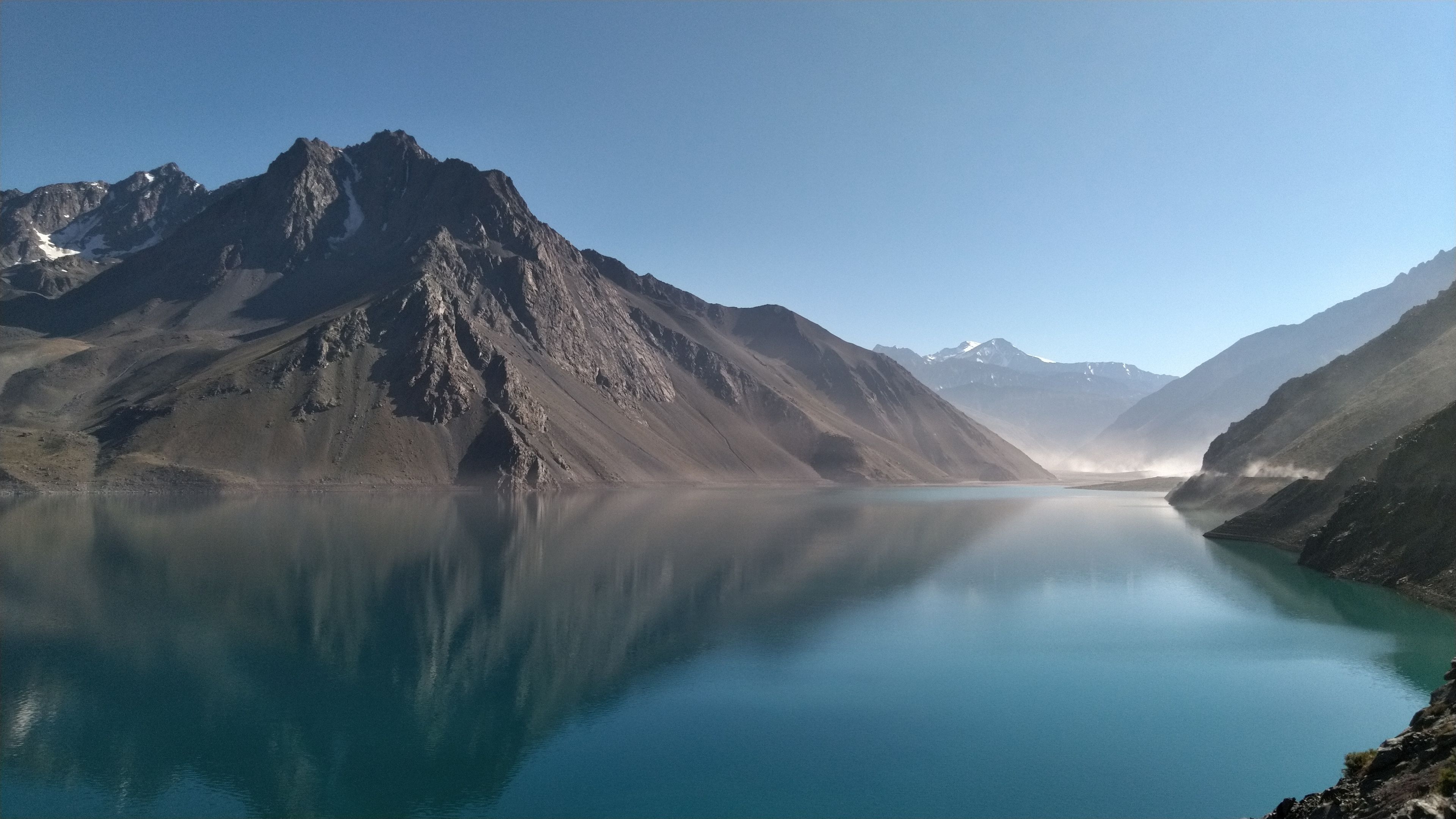 Una cordillera montañosa con un lago tranquilo que refleja las cumbres.