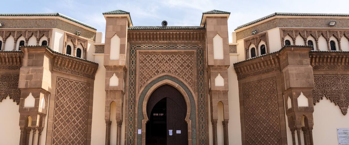 A grand entrance with intricate tile work, a large central archway, and a staircase leading up to it.