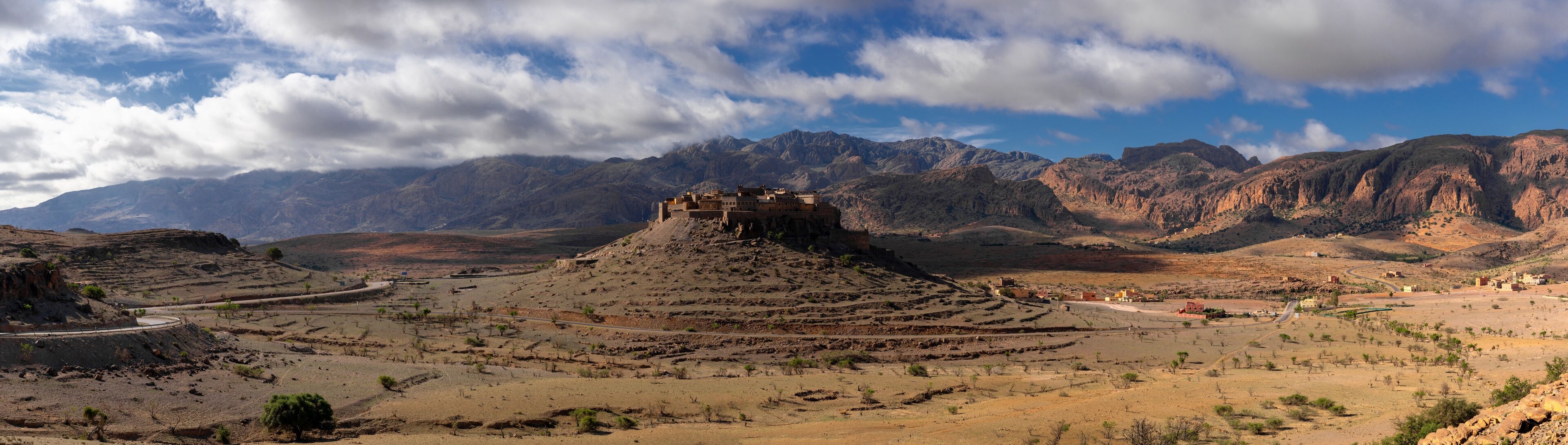 panorama landscape view of the Altas mountains in Morocco with the Kasbah Tizourgane on the hilltop in the centre