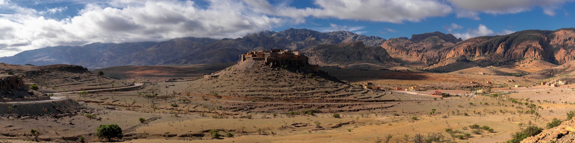 panorama landscape view of the Altas mountains in Morocco with the Kasbah Tizourgane on the hilltop in the centre