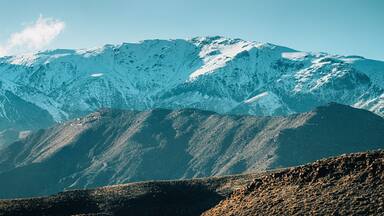 Stunning view of snow capped peaks rising above valleys in High Atlas mountain range, Morocco, creating breathtaking winter landscape