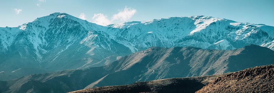 Stunning view of snow capped peaks rising above valleys in High Atlas mountain range, Morocco, creating breathtaking winter landscape
