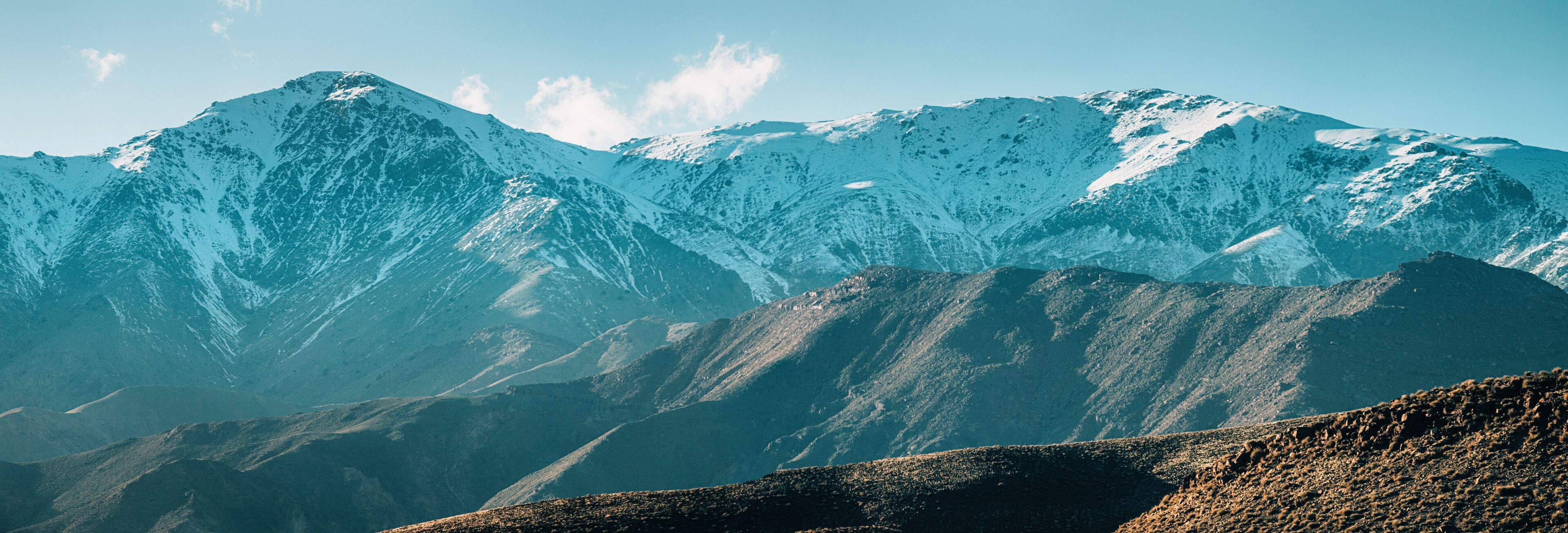 Snow-covered mountains with rugged terrain and rocky outcrops.