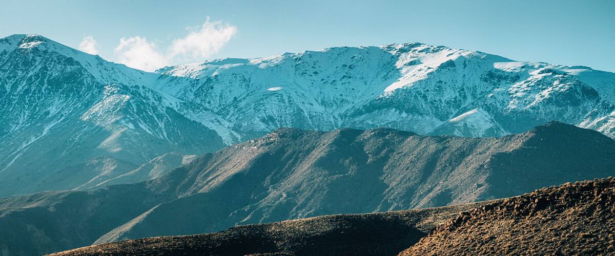 Snow-covered mountains with rugged terrain and rocky outcrops.