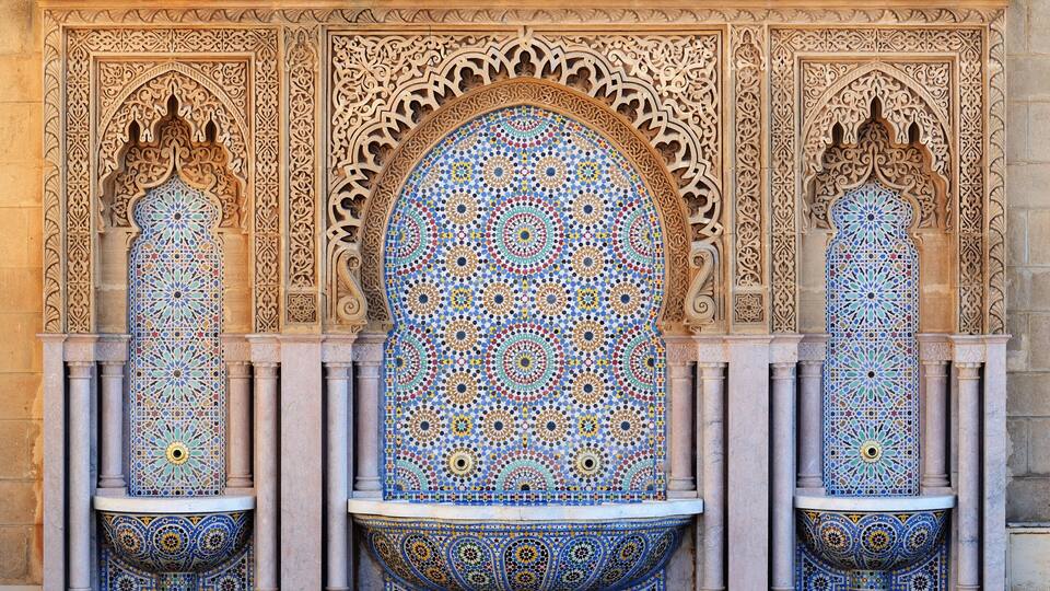 A detailed mosaic archway with intricate geometric patterns and a central circular design.