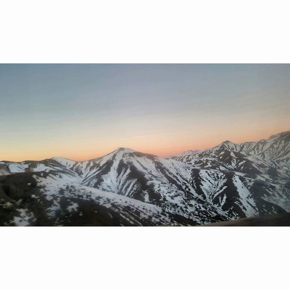 A mountain range with snow-covered peaks during sunset.
