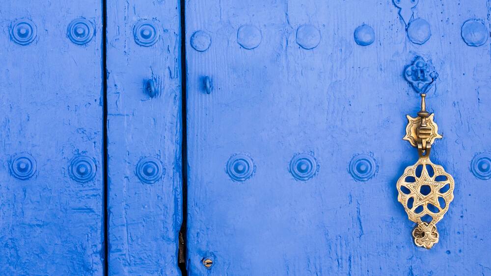 Background of traditional powder blue painted door with golde doorknocker