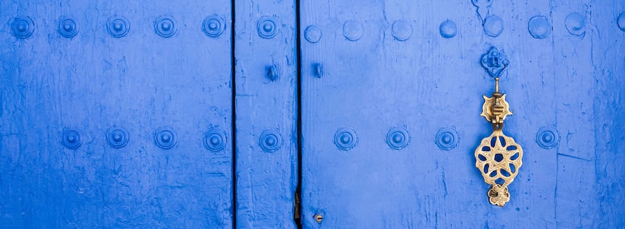 Background of traditional powder blue painted door with golde doorknocker