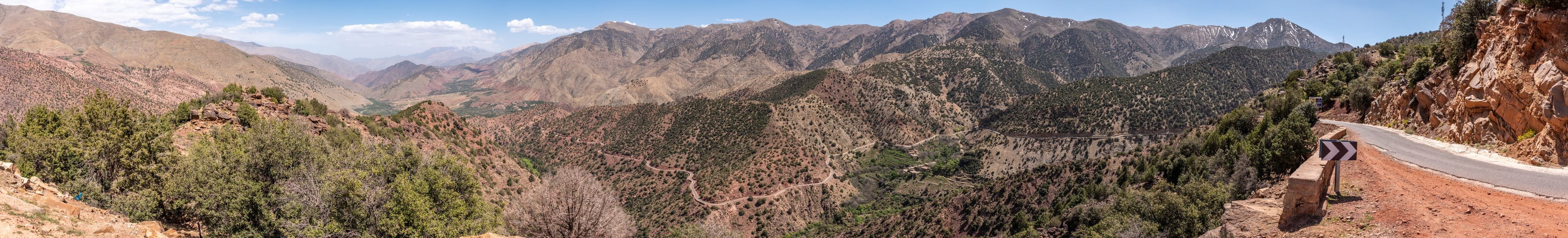 A mountainous landscape with a winding road and a signpost.