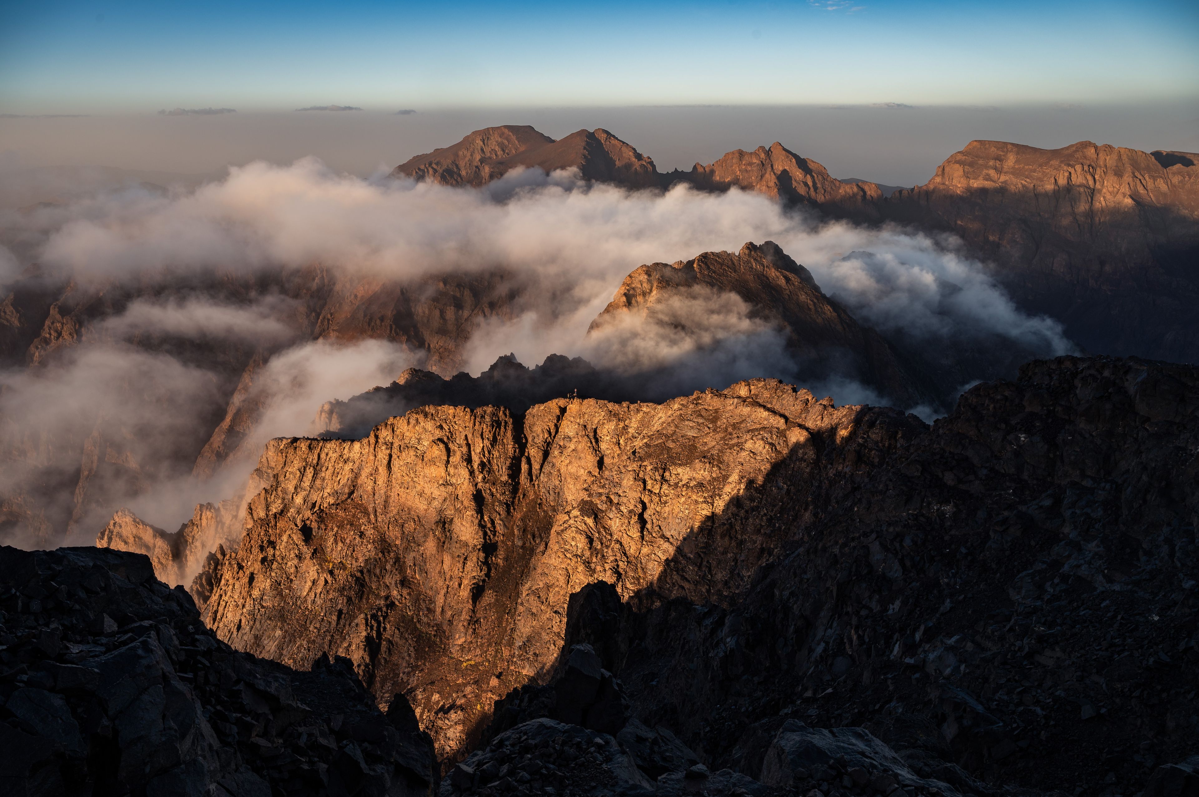 A mountain range with rugged peaks and a layer of clouds at the base.