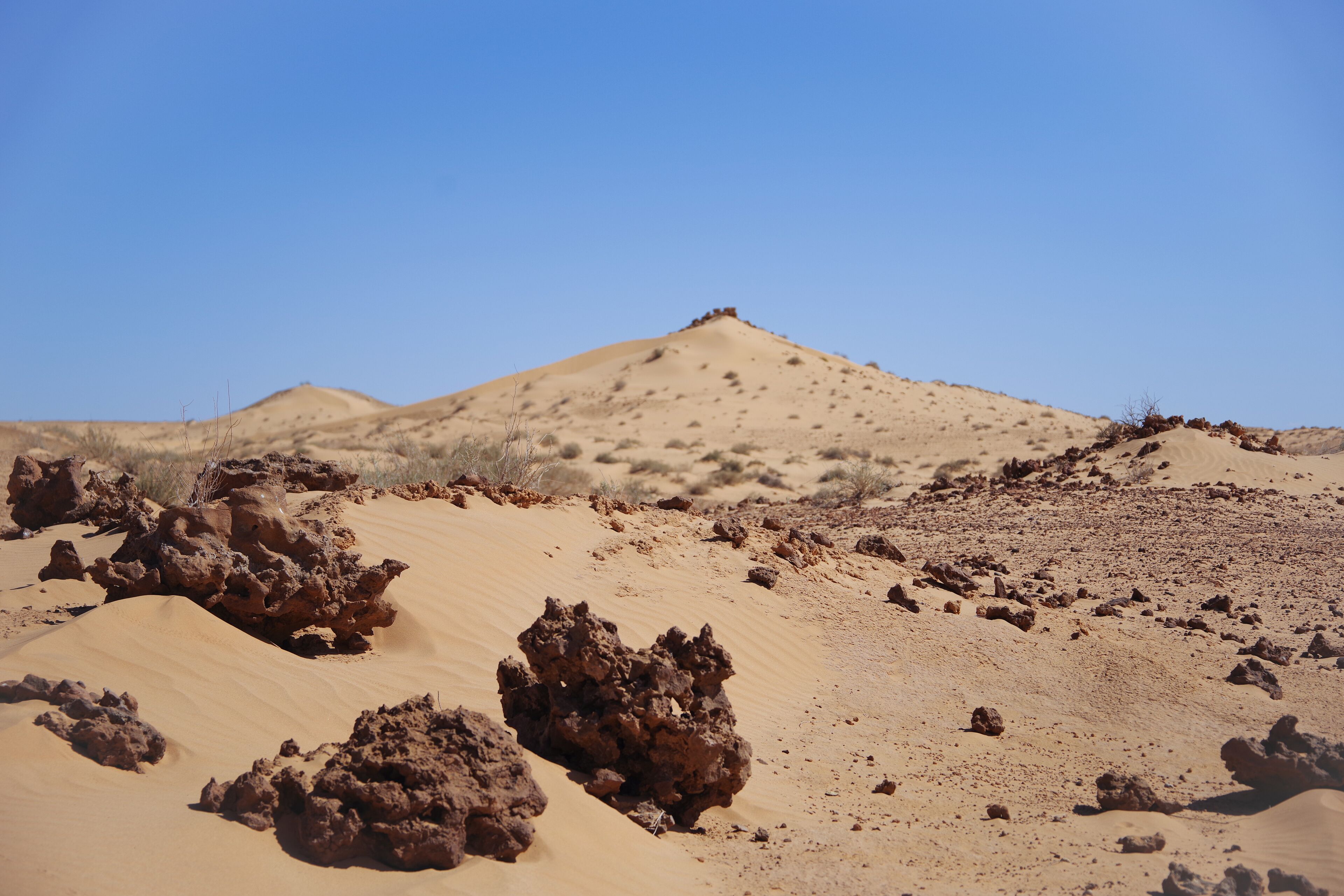 A desert landscape with sand dunes and rocky formations.
