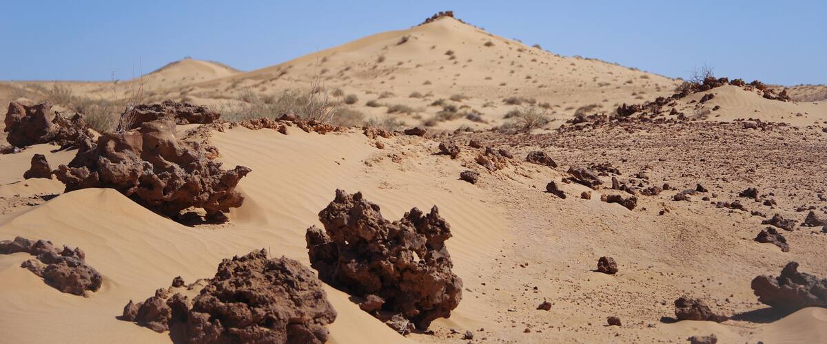 A desert landscape with sand dunes and rocky formations.