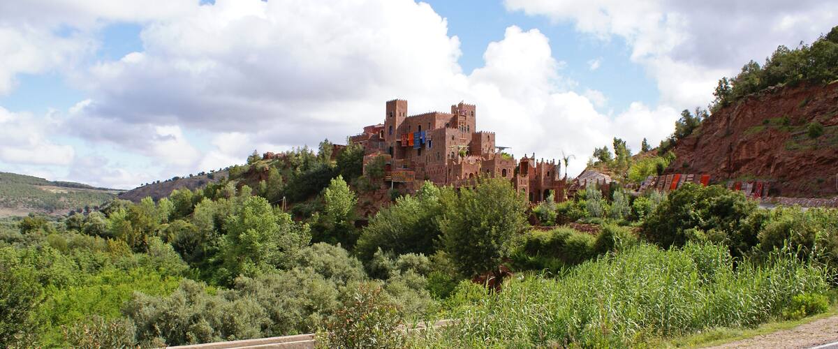 A historic castle on a hill surrounded by lush greenery.