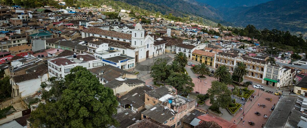 A town with a prominent church, surrounded by mountains and greenery.