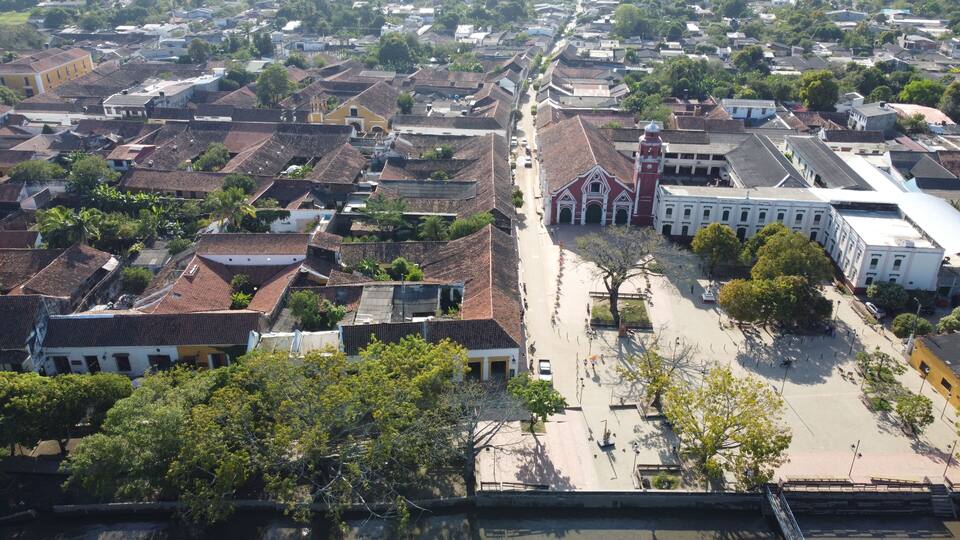 An aerial view of a historic town with traditional buildings, a central plaza, and a prominent church.