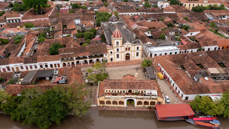 An aerial view of a historic town with a prominent church, a river, and traditional buildings.