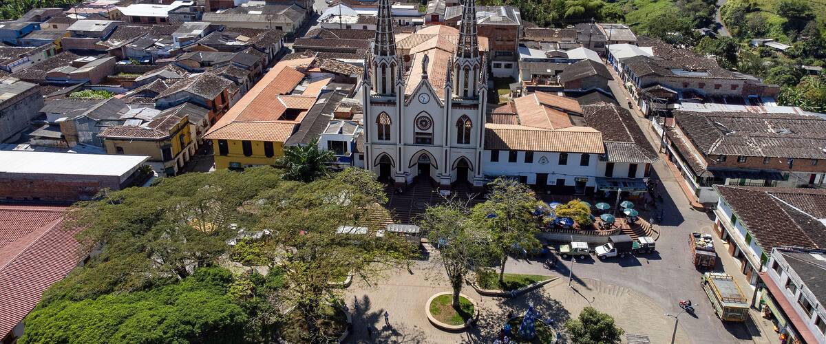 A historic town with a prominent church featuring two tall spires, surrounded by traditional buildings and lush greenery.